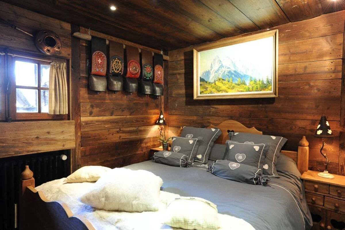 Una camera da letto in stile baita con un letto, cuscini, un quadro e una sveglia a parete.