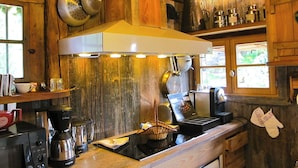A rustic kitchen with wooden walls, a stainless steel range hood, and various kitchen utensils. - Hôtel Les Chalets de Philippe avec Jacuzzis privatifs (Chamonix-Mont-Blanc)