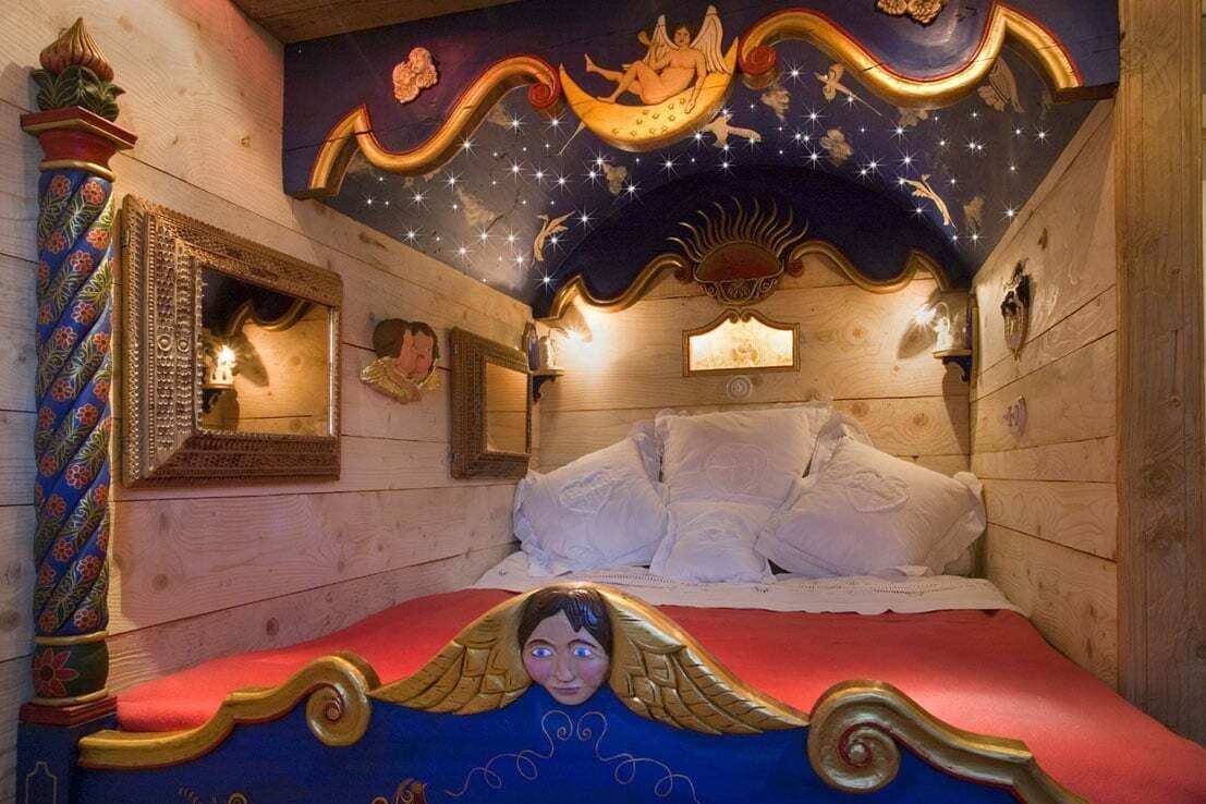 Ein Zimmer mit einem Bett, einem Spiegel und einer dekorativen Decke mit Halbmond und Sternen.