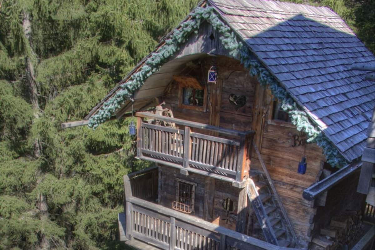 Una baita in legno con vasca idromassaggio, terrazza in legno e diversi balconi.