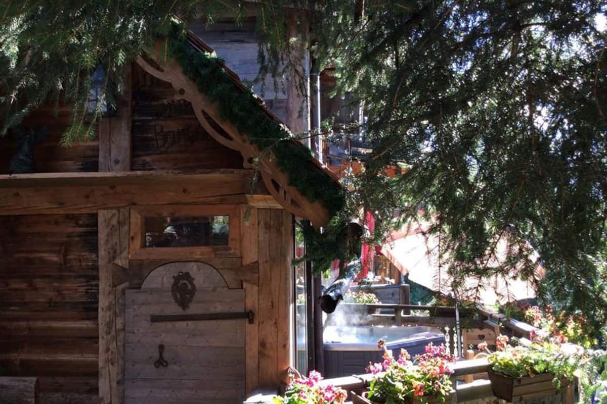 Un rustico chalet in legno con tetto spiovente, un camino ben visibile e una finestra con un elemento decorativo.