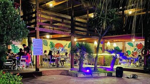 An outdoor restaurant with wooden beams and palm trees, featuring tables and chairs for dining. - Appart'hotel de charme  (Hammamet)