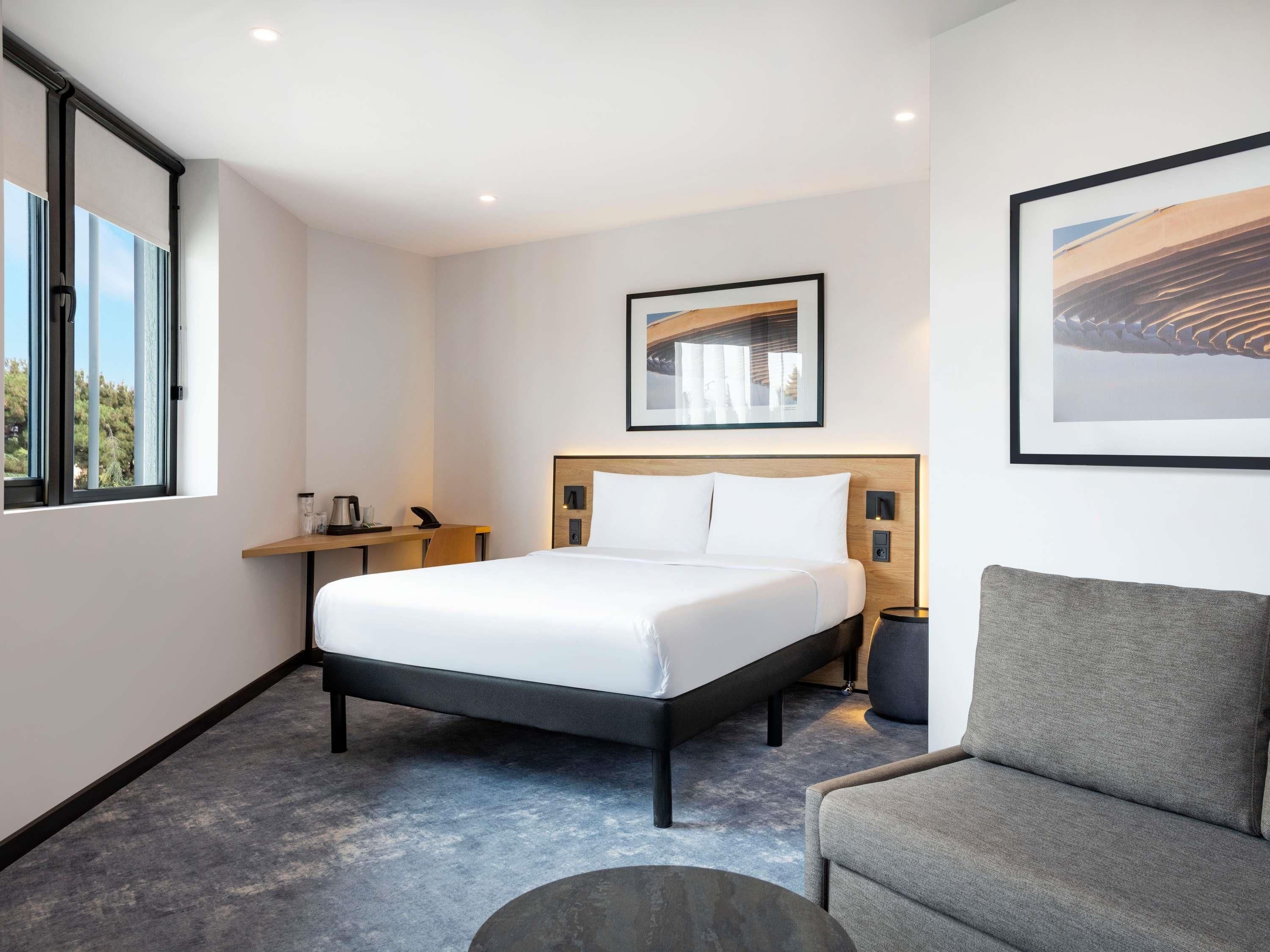 Habitación de hotel con cama, mesita de noche, silla y obras de arte en las paredes.