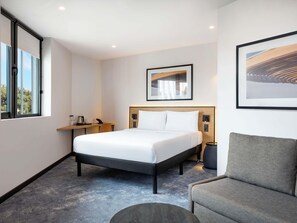 Habitación de hotel con cama, mesita de noche, silla y obras de arte en las paredes.