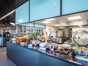Uma área de buffet com diversas opções, incluindo pratos quentes, saladas e bebidas.
