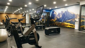 A gym with cardio machines, weightlifting equipment, and a large mountain mural. - Ibis Tbilisi Airport (Tbilisi)