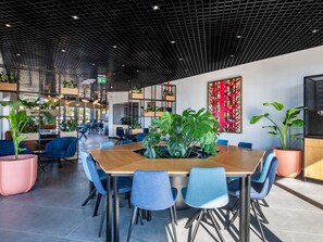 A modern conference room with a wooden table, blue chairs, and potted plants. - Ibis Tbilisi Airport (Tbilisi)