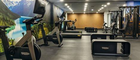 Un gimnasio con bicicletas estáticas, cinta de correr y máquinas de pesas.