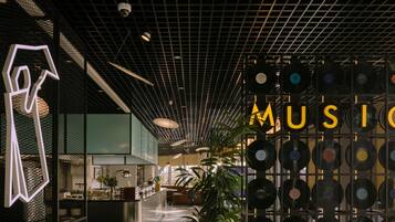 A modern interior with a vinyl record wall, a geometric light installation, and a central bar area.