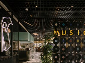 A modern interior with a vinyl record wall, a geometric light installation, and a central bar area. - Ibis Tbilisi Airport (Tbilisi)