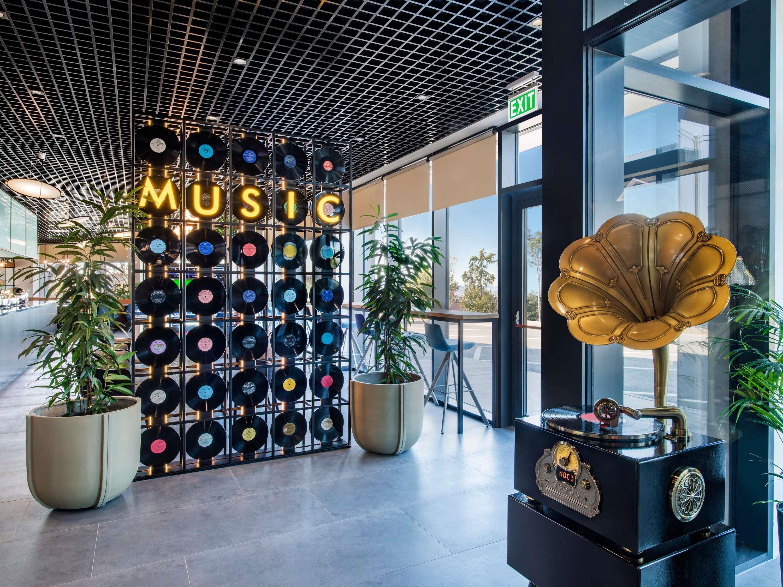 A modern interior with a wall of vinyl records, a vintage gramophone, and potted plants.