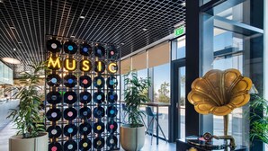 A modern interior with a wall of vinyl records, a vintage gramophone, and potted plants. - Ibis Tbilisi Airport (Tbilisi)