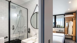 A modern bathroom with a glass-enclosed shower, a white sink, and a large mirror.