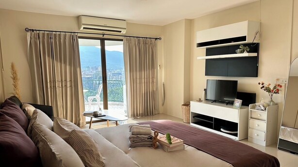 A modern hotel room with a large bed, a TV, and a balcony with a view.