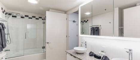 A modern bathroom with a glass-enclosed shower, a white sink, and a large mirror.
