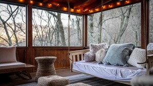 A cozy cabin interior with a wooden bench, a hanging swing, and a cushioned bench with pillows. - Round Top Way Cabin by Beyond Expectations: 6BR Luxury Cabin w/ Hot Tub & Sauna (Sevierville)