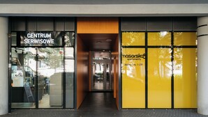 A building entrance with a sign reading "CENTRUM SERWISOWE" and another sign for "masorskotapetyy" with a contact number. - Native Apartments Masarska 8 (Kraków)