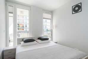 Ein Hotelzimmer mit einem Bett, zwei Kissen, einem Nachttisch, einer Lampe und einer gerahmten Schallplatte an der Wand.