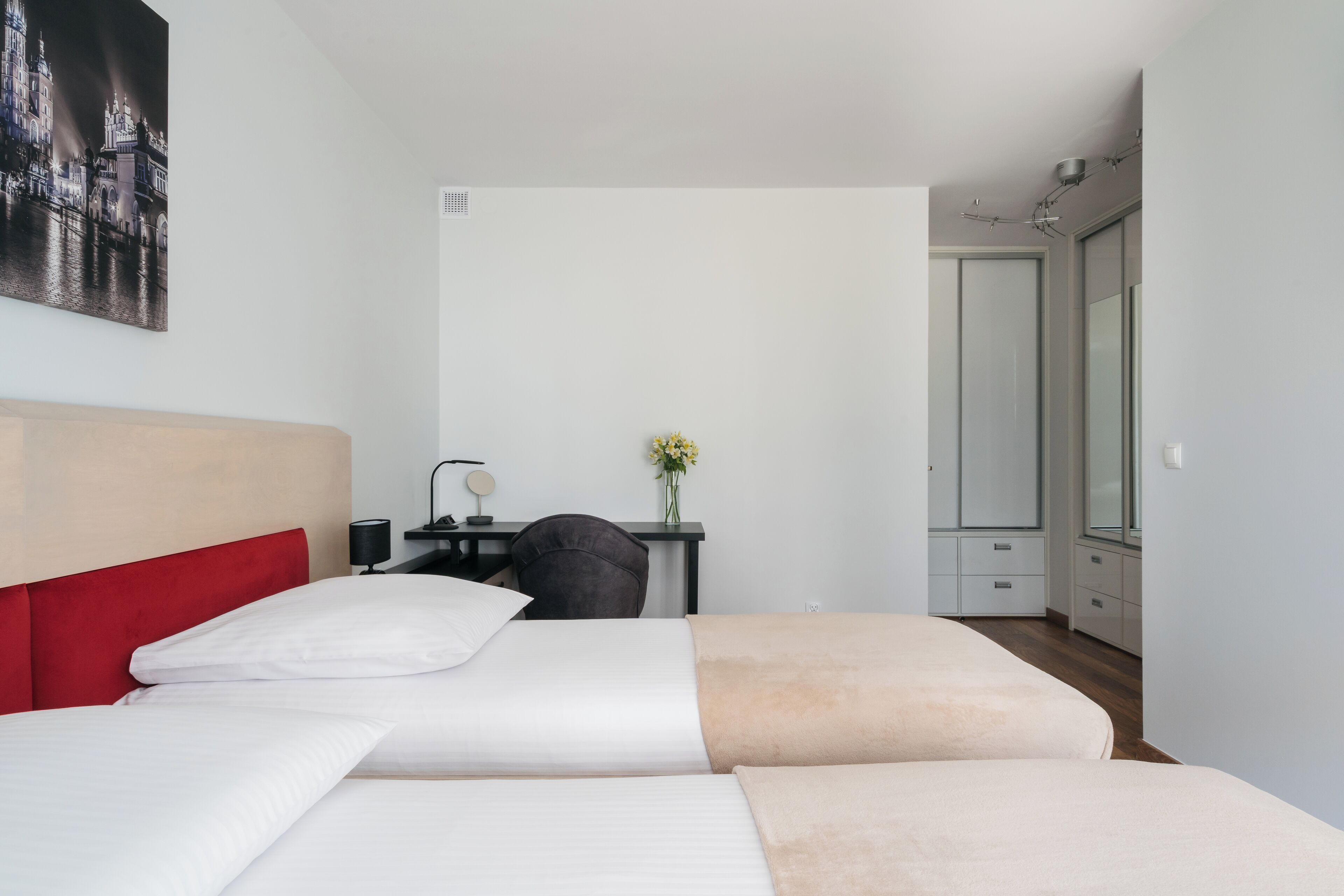 A hotel room with two beds, a desk, a chair, a mirror, and a wardrobe.
