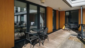 An outdoor patio area with a round table and chairs, large sliding glass doors, and a wooden deck. - Native Apartments Masarska 8 (Kraków)