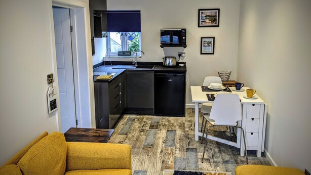 A compact living space with a kitchenette, a dining area, and a sofa. - The Orchid (Gillingham)