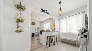 A modern kitchen with a central island, bar stools, and a decorative wall with a 'Jather' sign. - Magnolia Blossom ,1920's Charm Meets Modern Luxury (Waco)