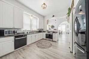 Una cocina moderna con armarios blancos, microondas integrado, estufa y lavavajillas.