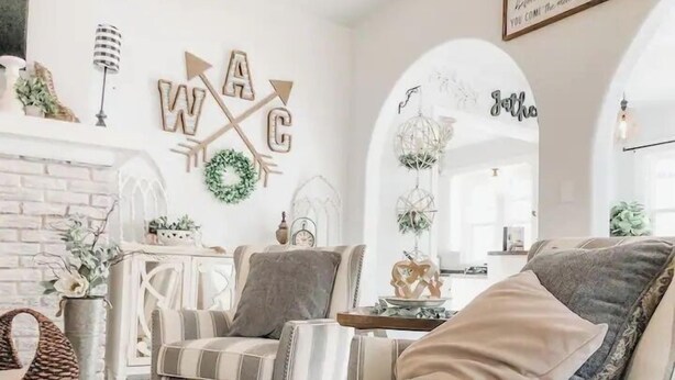 A cozy living room with a fireplace, striped armchairs, and decorative wall art. - Magnolia Blossom ,1920's Charm Meets Modern Luxury (Waco)
