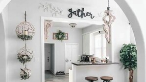A kitchen with a white archway, hanging spherical light fixtures, and a 'Jather' sign. - Magnolia Blossom ,1920's Charm Meets Modern Luxury (Waco)