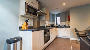 A modern kitchen with wooden cabinets, a stainless steel microwave, and a built-in oven. - Two Bedroom Newcastle City Quayside Apartment (Newcastle-upon-Tyne)