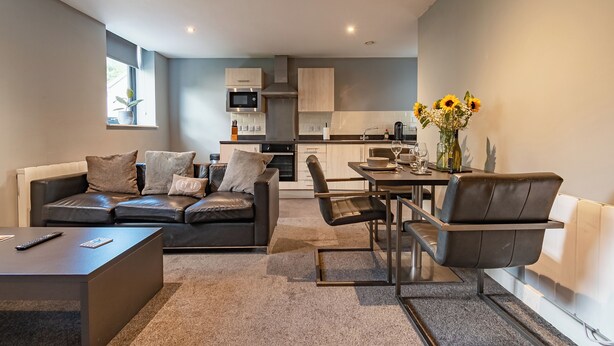 A modern living room with a sofa, coffee table, and dining area. - Two Bedroom Newcastle City Quayside Apartment (Newcastle-upon-Tyne)
