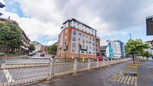 A multi-story building with a modern architectural design, featuring a mix of brick and white facades, and a gated entrance. - Two Bedroom Newcastle City Quayside Apartment (Newcastle-upon-Tyne)