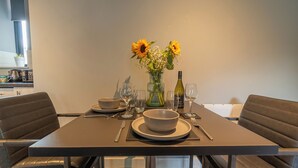 A dining table set with a bowl, wine glasses, and a vase with flowers. - Two Bedroom Newcastle City Quayside Apartment (Newcastle-upon-Tyne)