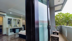 A hotel room with a balcony, a small table with a vase, and a bed.