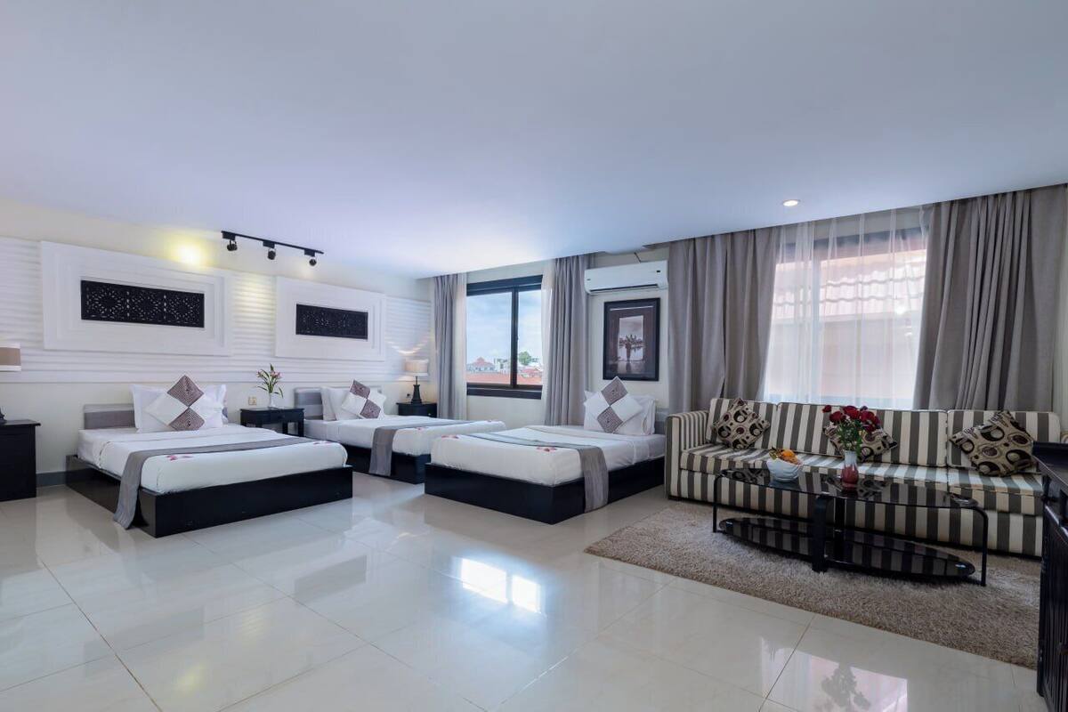 Una habitación de hotel moderna con dos camas, un sofá, una mesa de centro y vistas a la ciudad.