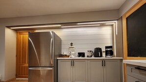 Una cucina moderna con frigorifero in acciaio inossidabile, mobili in legno e un piano di lavoro con una macchina da caffè e altri elettrodomestici.