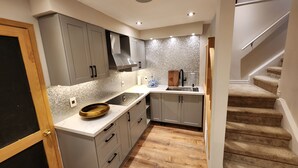 Una cucina moderna con mobili grigi, una ciotola di legno sul piano di lavoro e uno schienale piastrellato.