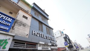 En byggnad med en skylt för hotellet Sai Inn Rooms, en skylt för Jay Ambe, som utför mobilreparationer, och en skylt för Capital Bank.