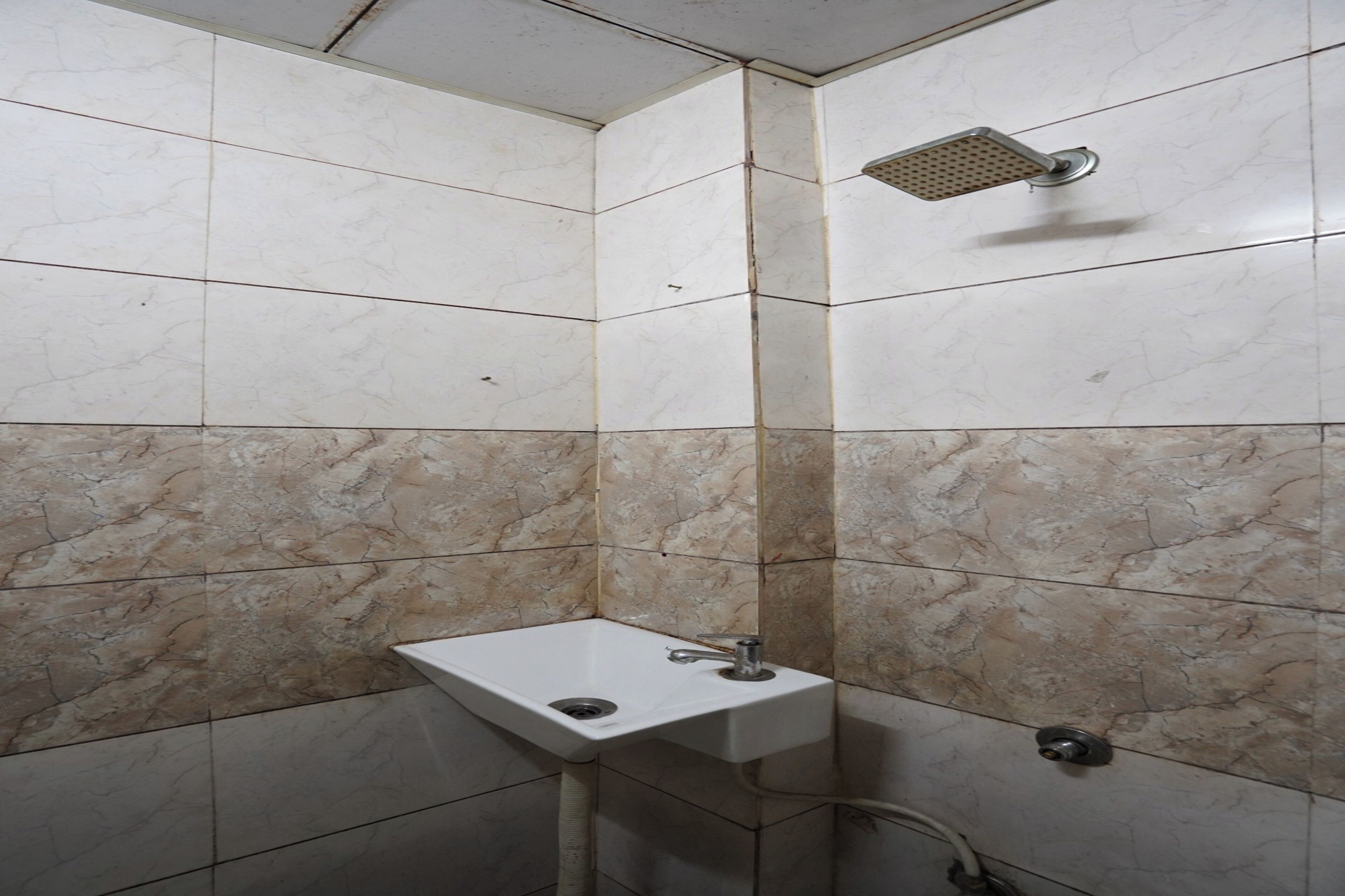 Een badkamer met een wastafel, douche en betegelde wanden.