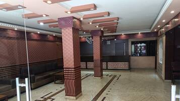 Un vestíbul amb columnes decorades, una recepció i una zona de seients.