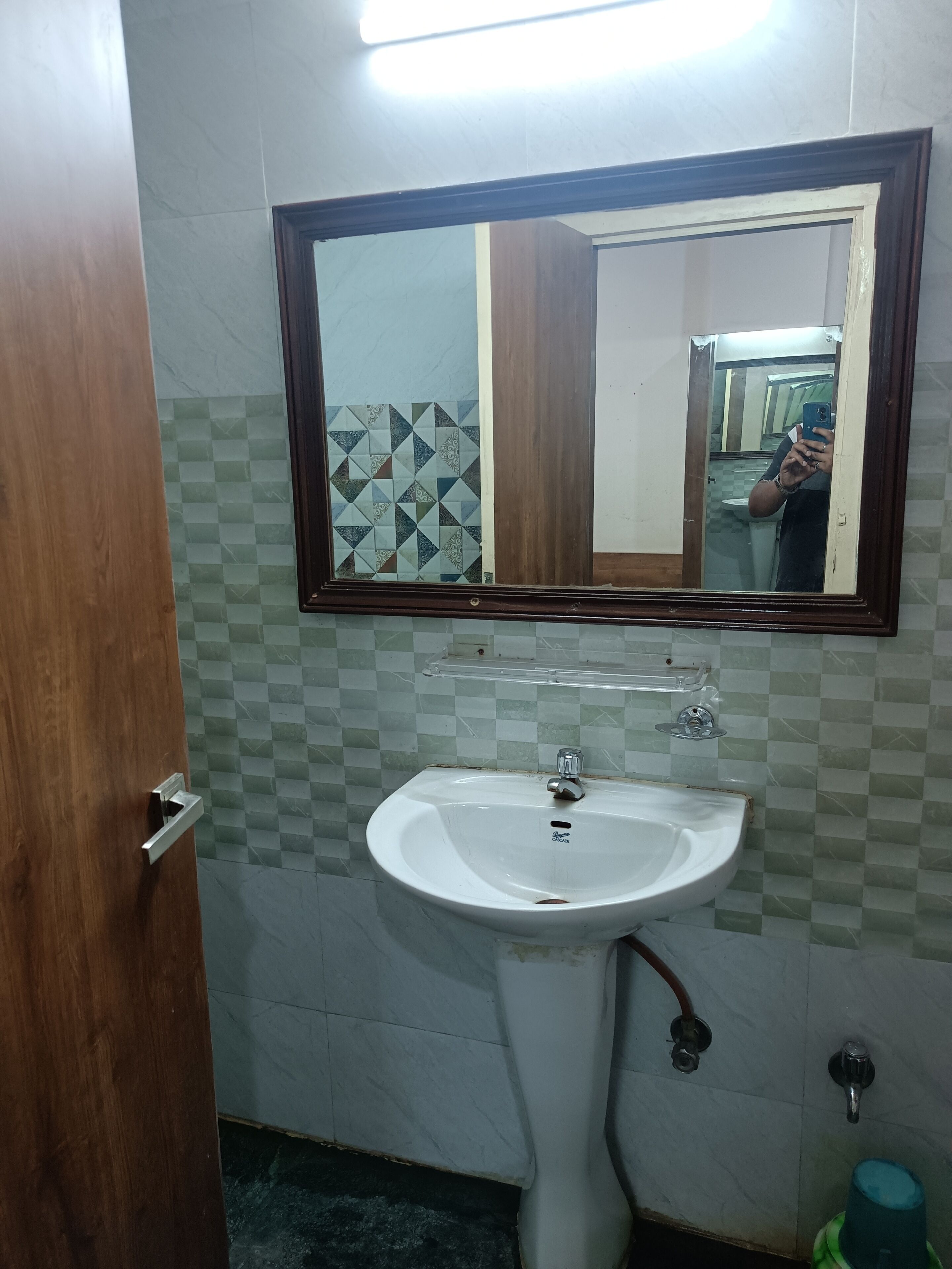 A bathroom with a white sink, a mirror with a wooden frame, and patterned tiles on the walls.
