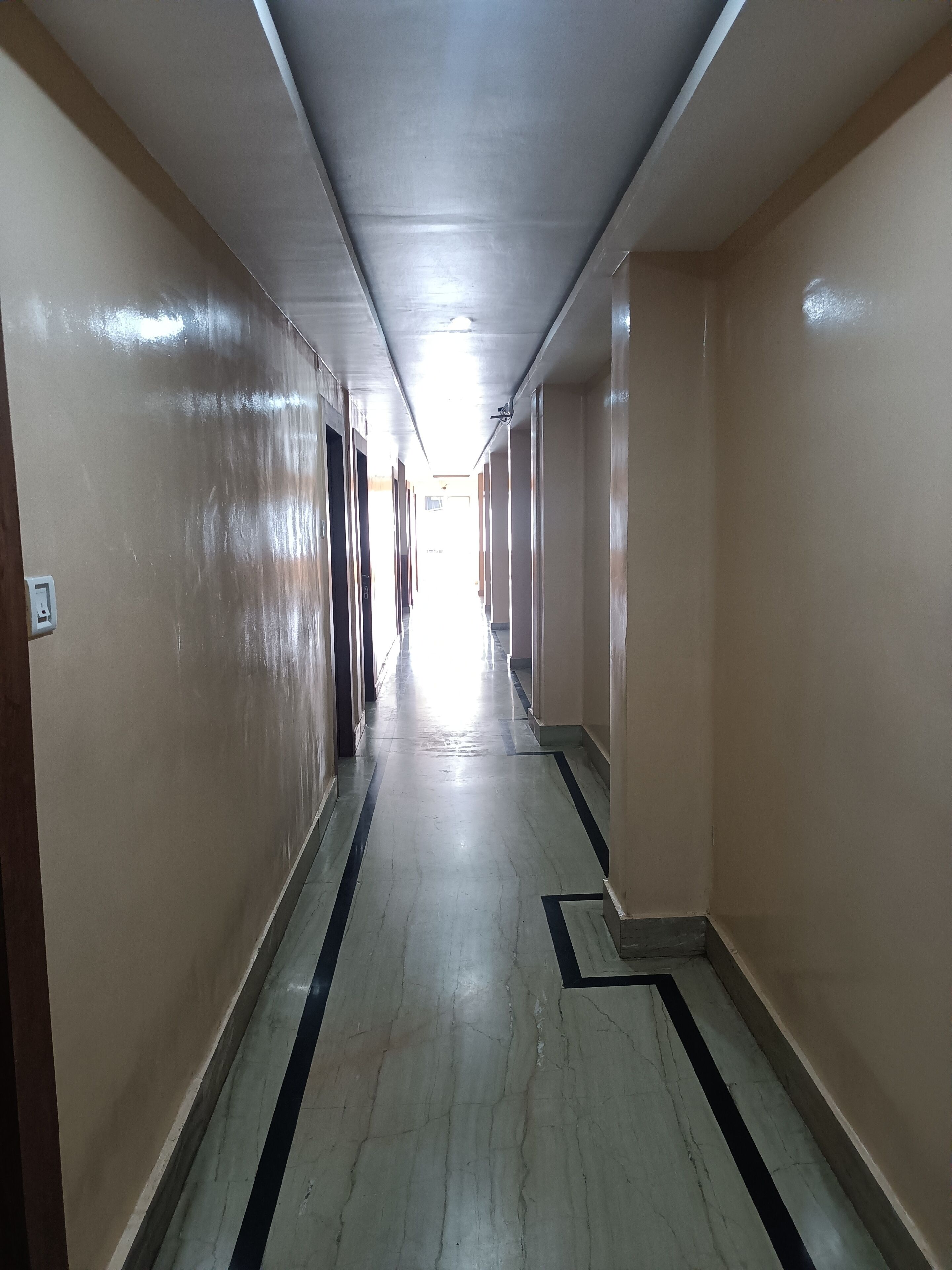 A long, narrow hallway with beige walls and a marble floor.