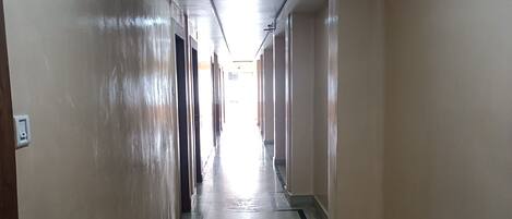 A long, narrow hallway with beige walls and a marble floor.