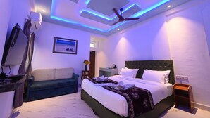 Una moderna camera d'albergo con un letto, un divano, una televisione e una ventola a soffitto.