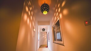 Un corridoio con pavimento decorato, una lampada a soffitto e una finestra a destra.
