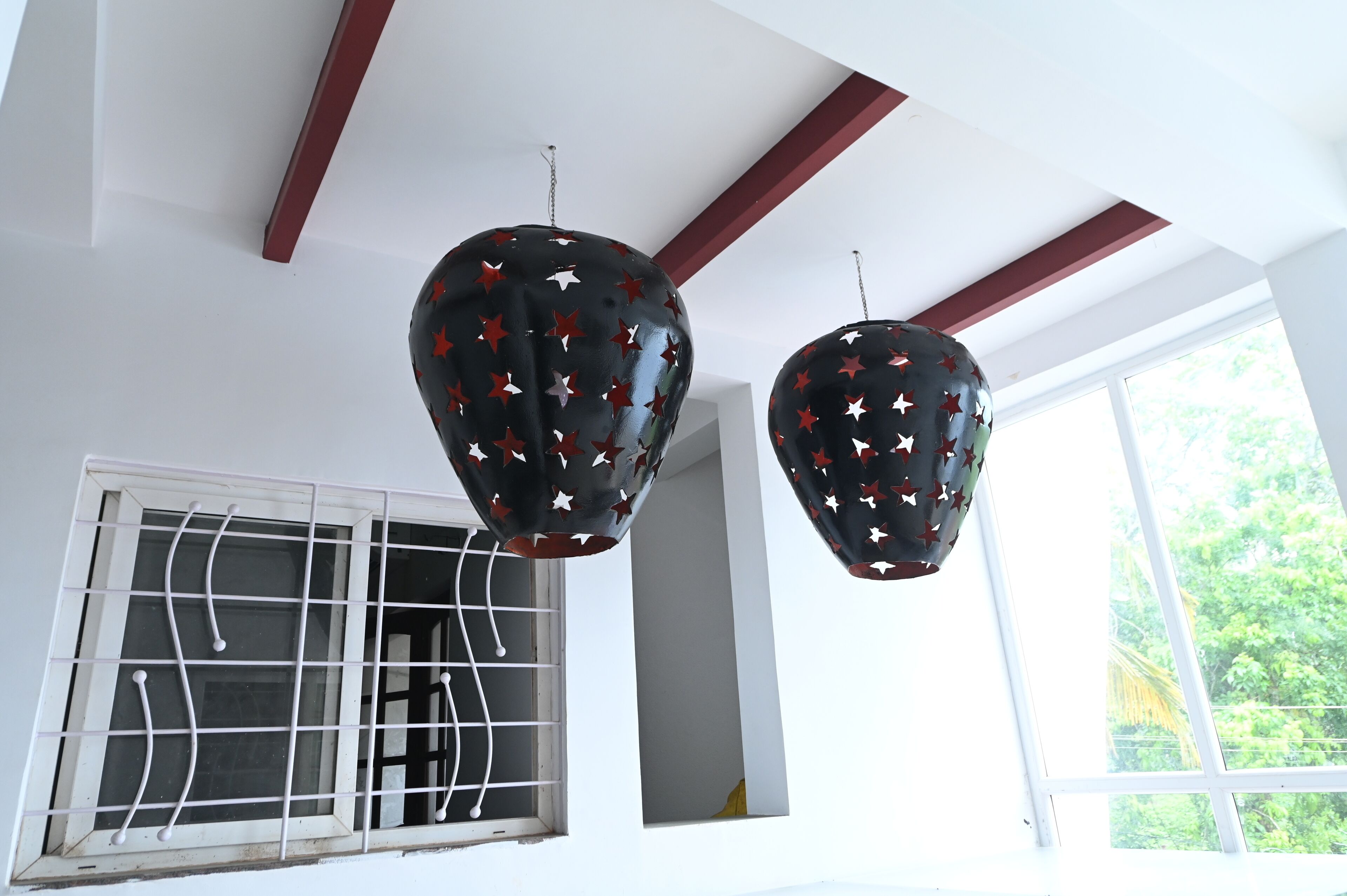 Zwei schwarze, runde Kronleuchter mit roten und weißen Sternmustern hängen von der Decke.