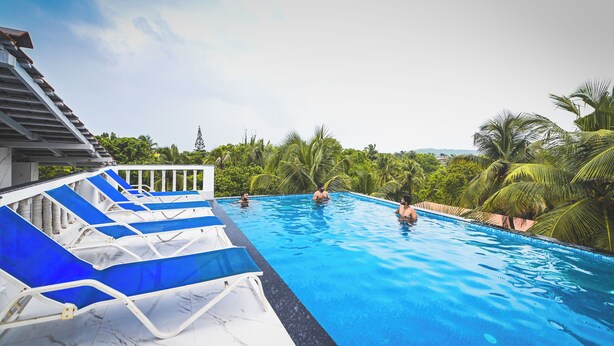 Una piscina con poltroncine blu e palme sullo sfondo.