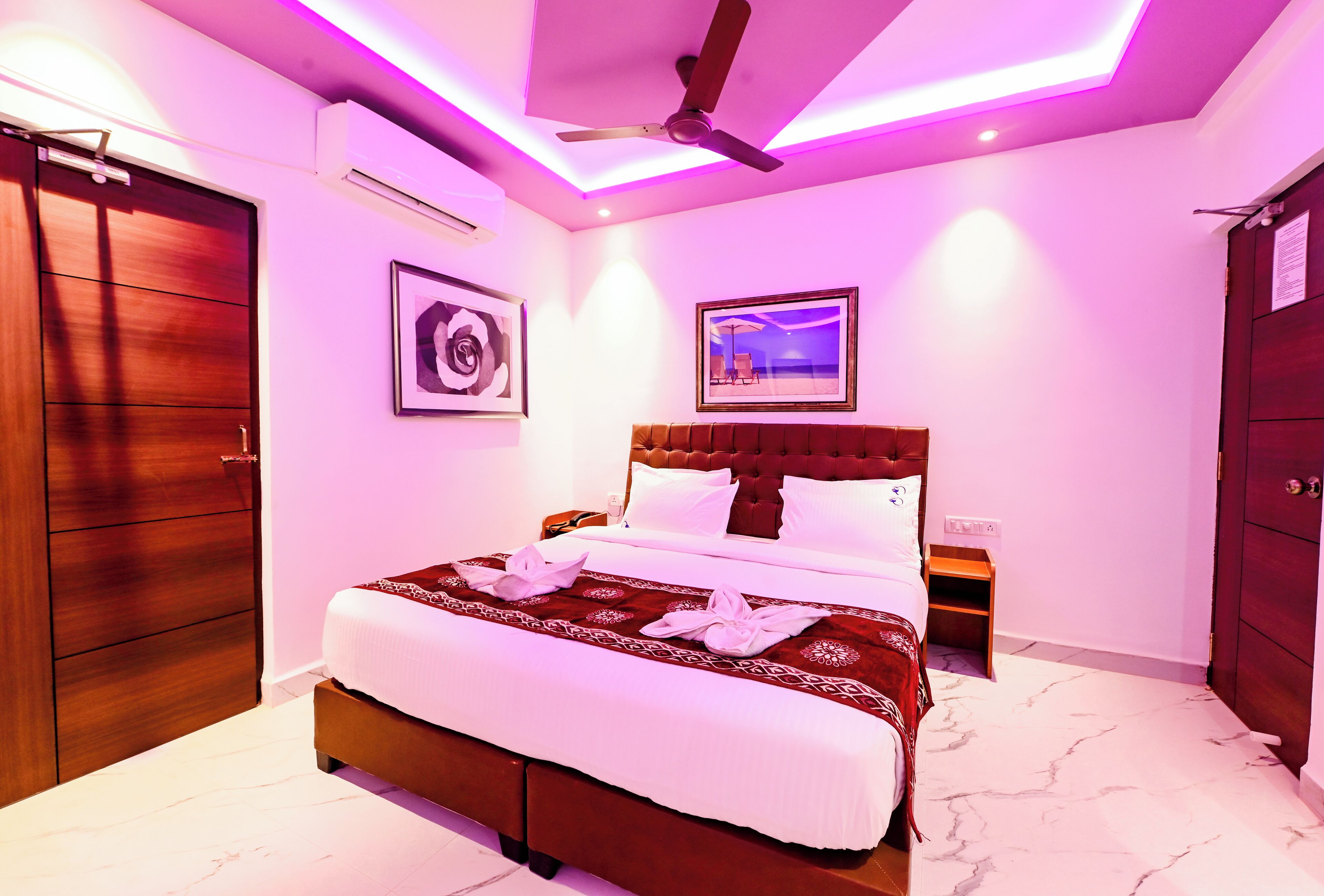 A hotel room with a large bed, a ceiling fan, and a marble floor.