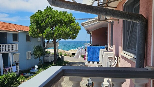 A balcony with a view of the sea, a tree, and a building with a balcony. - Apartment M & VALENTIN (Nin)