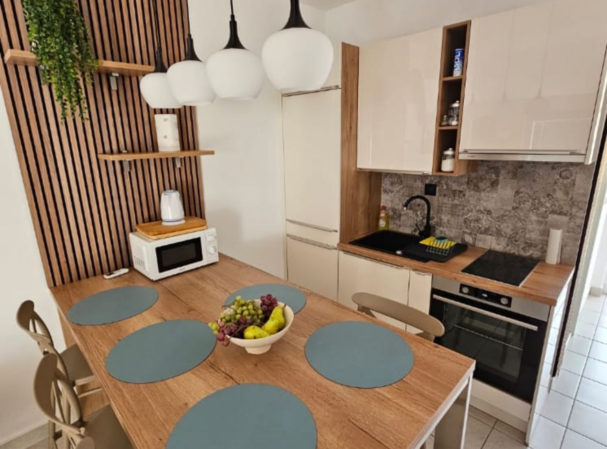 Una cocina moderna con una mesa de comedor de madera, un cuenco de fruta y un horno empotrado.